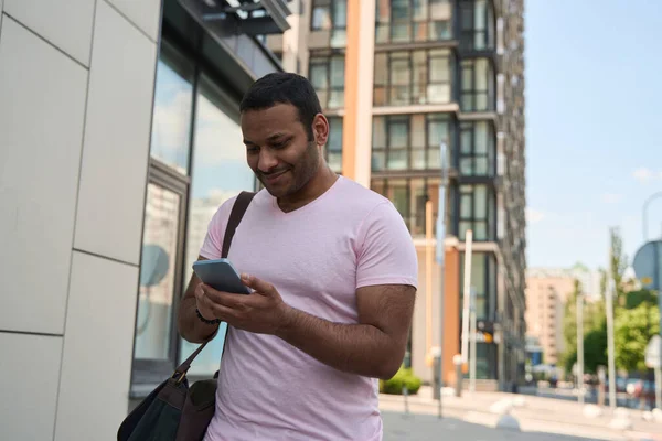 Usmívající Muž Stojí Poblíž Kancelářské Budovy Dívá Obrazovku Mobilního Telefonu — Stock fotografie