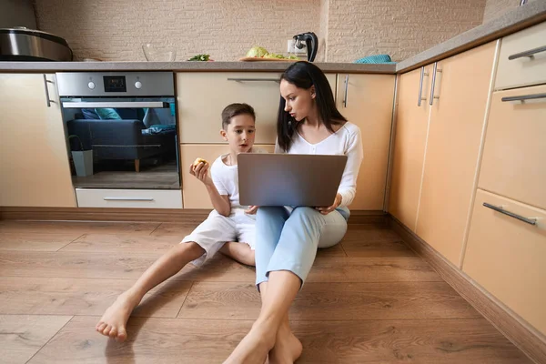 Boy Eating Apple While Looking Laptop Screen His Mother Knee — ストック写真