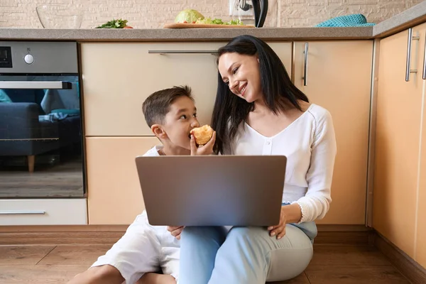 Boy Taking Bite Apple Looking Smiling Mother While Sitting Kitchen — ストック写真