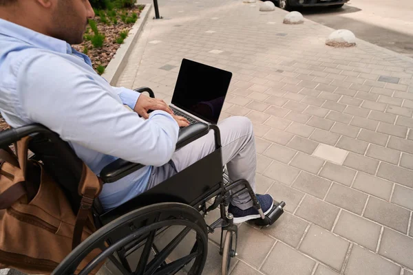 Cropped Photo Disabled Male Person Sitting Wheelchair Typing Laptop — Zdjęcie stockowe
