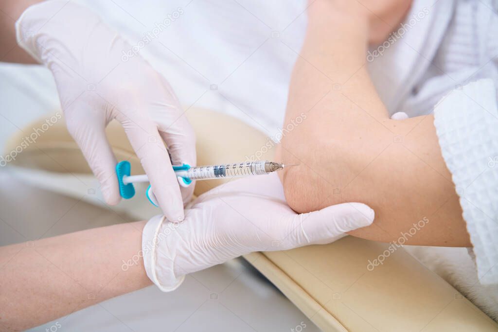 Injections with a syringe in the elbow for skin tightening
