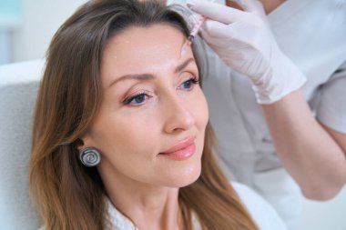 Alnındaki cilt yenilenmesi için doktora giden güzel bir kadın. Mezoterapi enjeksiyonuyla.
