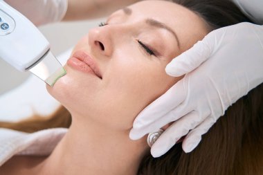 Woman on the procedure of hardware facial cleansing in the medical and cosmetology center