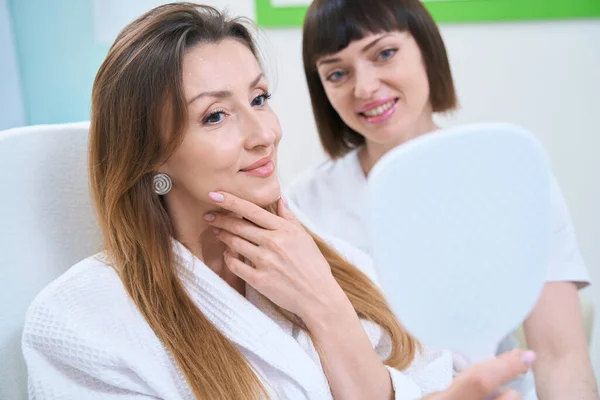 Client Aesthetic Medicine Clinic Looks Mirror Procedure Attentive Gaze Doctor — Foto Stock