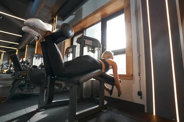 Atleta Profissional Feminino Realizando Curl Perna Com Máquina Peso Durante — Fotografia de Stock