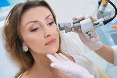 Klinikteki hastanın yüzünde lazer çıkarma prosedürü var.