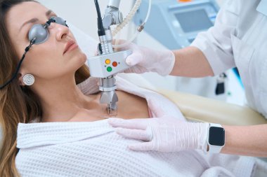 Klinikteki hasta kozmetoloji kliniğinde lazer temizleme prosedürüyle uğraşıyor.