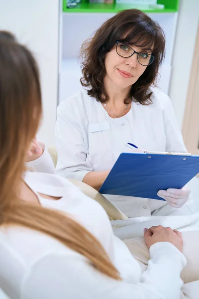 Vrouw Dermatoloog Bril Schrijft Gegevens Klant Een Medische Kaart — Stockfoto