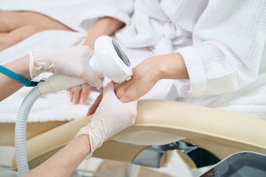 Doctor heals and rejuvenates the skin of the hands using phototherapy