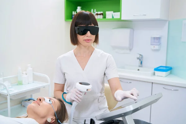 Doctor and patient in goggles on skin photorejuvenation procedure in cosmetology center