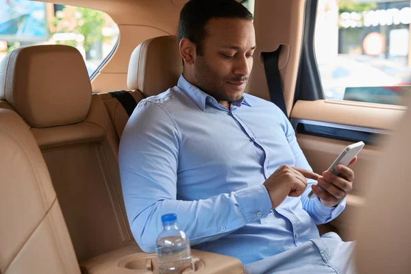 Focused Young Male Passenger Sitting Taxi Texting His Smartphone — стоковое фото