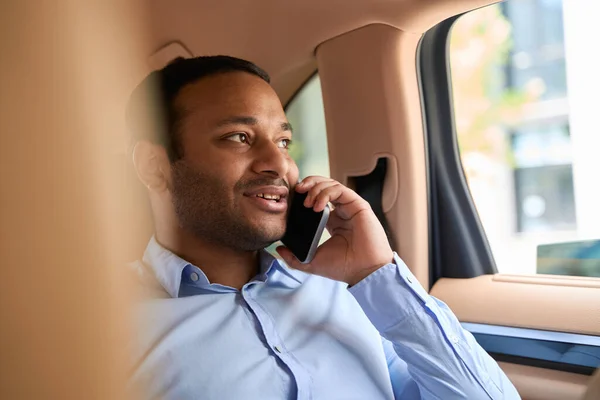 Portrait of passenger seated in backseat of car having conversation on smartphone