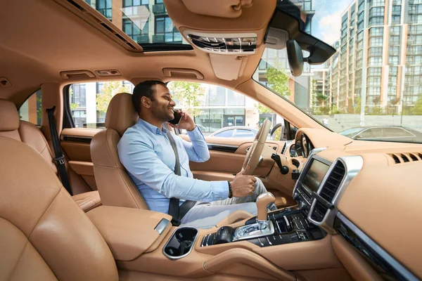 Side View Joyous Driver Seated Steering Wheel Automobile Talking Smartphone — стоковое фото