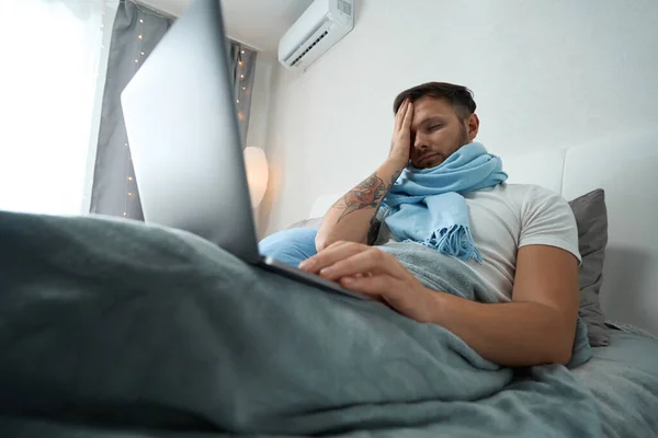 Baş Ağrısı Olan Genç Bir Adam Dizüstü Bilgisayarla Yatakta Yatıyor — Stok fotoğraf