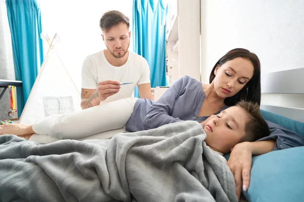 Saddened Young Parents Bedside Sick Son Surrounded Care Love — стоковое фото