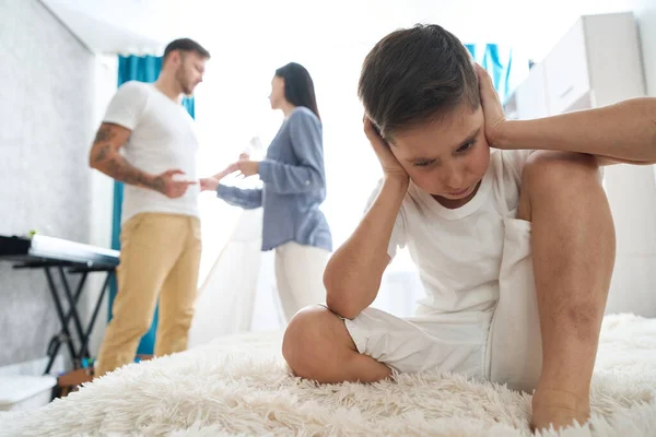 Parents sort things out in children room with the child, boy is scared, he does not want to hear insults