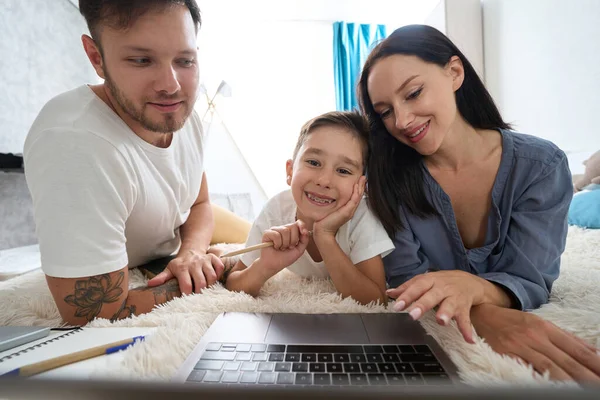 Kind and caring parents help teen son with homework at home schooling