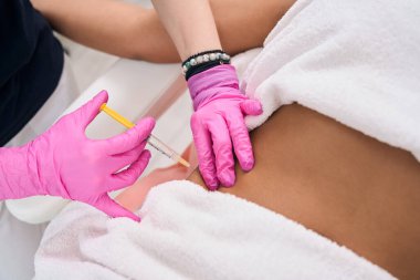 Estetik tıp kliniğinde kaldırma işlemi yapan bir kadın karnının altında iğne olur.