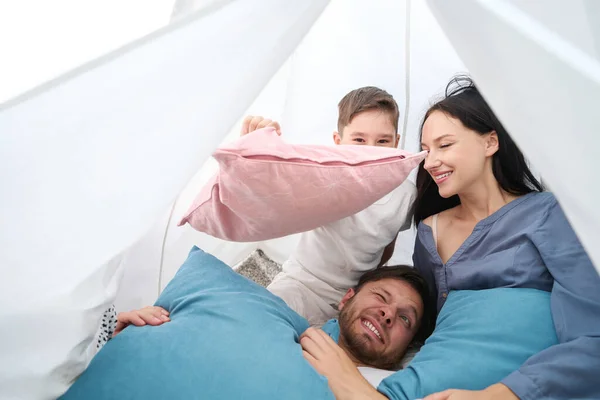 Mom and son jokingly threw pillows at dad, small family is comfortable in a hut