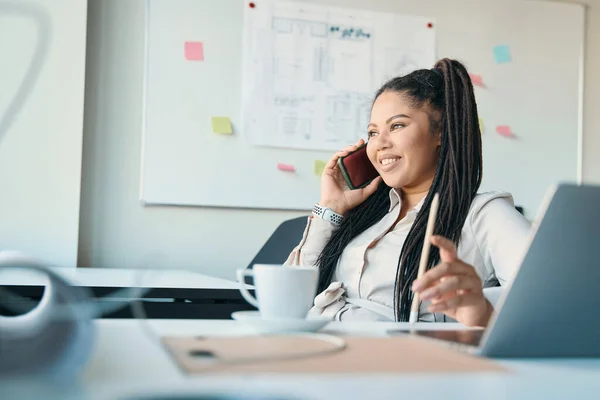 Smiling Female Entrepreneur Sitting Office Desk Looking Distance Phone Talk — Stockfoto