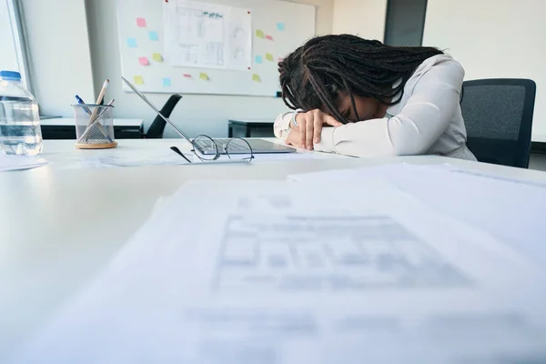 Exhausted company employee dozing off on office table in front of laptop