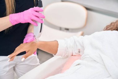Safe procedure of laser hair removal of hands in a modern aesthetic medicine salon