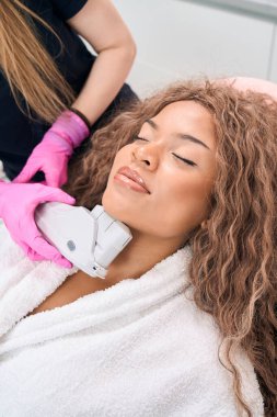 Young patient in the clinic of aesthetic cosmetology on painless high-tech hardware procedure of smas-lifting of the chin area