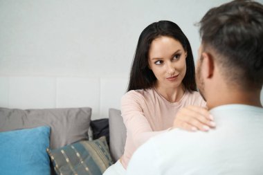 Genç bir kadın ellerini bir erkeğin omuzlarına koydu, ama erkek arkadaşına inançsızlıkla baktı.