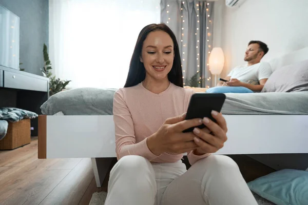Beautiful Couple Resting Spacious Bedroom Smiling Woman Has Phone Her — Fotografia de Stock
