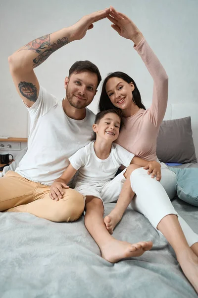 Family photo session of a beautiful young family of dad, mom and son on a cozy bed
