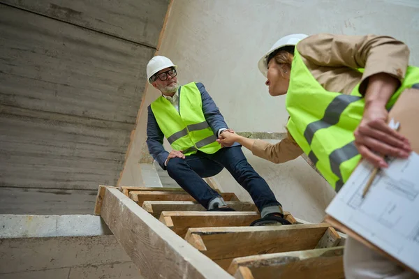 Adult Male Foreman Helps Beautiful Woman Realtor Climb Wooden Staircase — Stockfoto