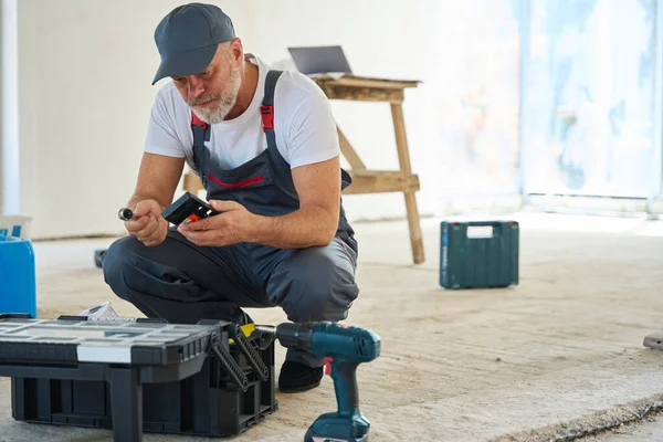 Focused Builder Looking Sitting Open Toolbox Looking Tool His Hand — ストック写真