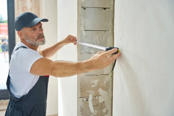 Gray Haired Bearded Builder Measures Width Doorway Tape Measure Man — Stockfoto