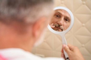 Man sitting in front of a mirror skin care cosmetics. Cropped view