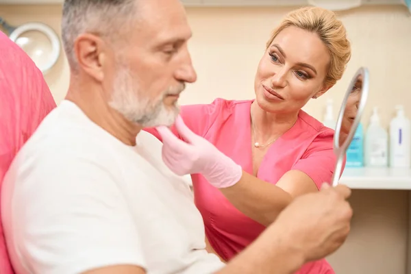 Gray Haired Man Looks Mirror Woman Beautician Examines His Face — Stock Photo, Image