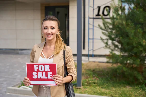 Smiling Woman Realtor Stands Sign Her Hands Sale Front House — Fotografia de Stock