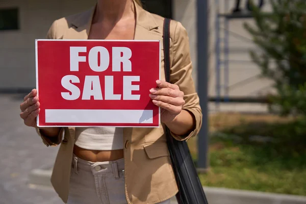 Female Realtor Stands Red Sign Her Hands Sale Front House — Stock fotografie