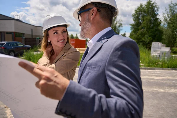 Woman Realtor Looks Client Protective Helmet Who Holds Drawing House — Stockfoto