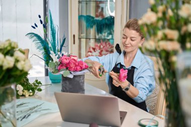 Experienced florist cuts off long flower stem with garden shears. Online lesson on creating compositions in round box
