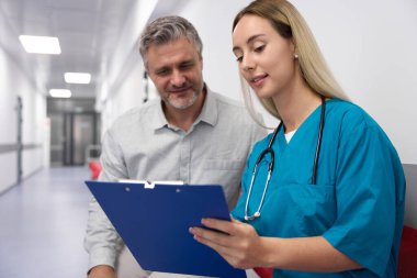 European female doctor with long hair showing documents to handsome male patient