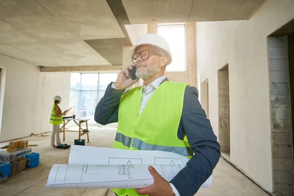 Foreman Holds Folded Drawings His Hands Speaks Mobile Phone While — Stockfoto