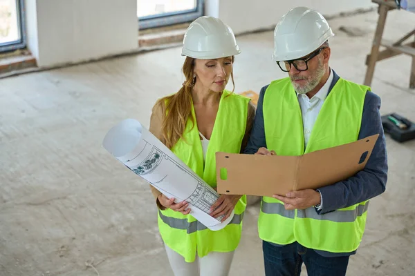 Male Foreman Holds Open Folder Discusses Project Realtor Standing Unfinished — Fotografia de Stock