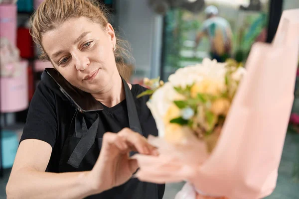 Close Photo Female Florist Adjusting Wrapping Paper Bouquet Talking Phone —  Fotos de Stock