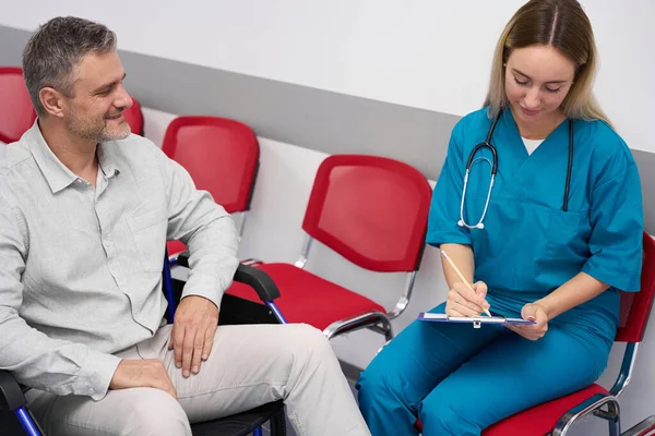 Woman Doctor Writing Document While Disabled Patient Smiling While Sitting — Stockfoto