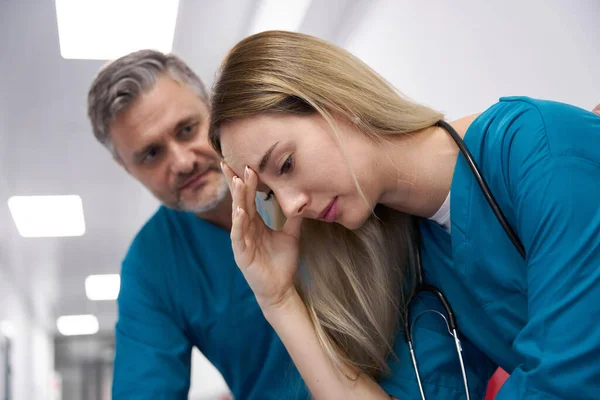 Woman doctor sits sad and caucasian man doctor consoles her