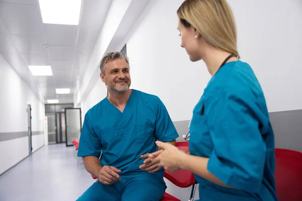 Doctors in blue uniforms are smiling and chatting with each other in the lobby of the hospital