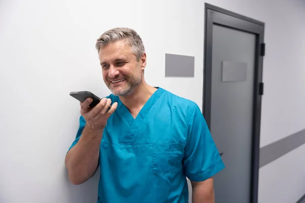 Man in a medical suit speaks on the phone against the wall