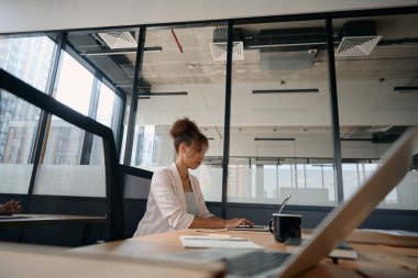 Focused african american woman working on laptop while in loft style coworking space. Workspace for efficient work
