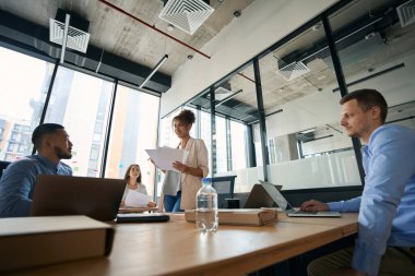 Photo of a meeting of young colleagues to discuss work issues. Spacious office with large windows