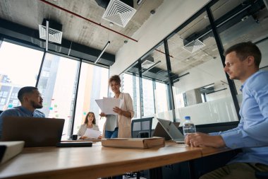 Team of professionals consisting of young men and women are talking at a conference in a large fashionable office